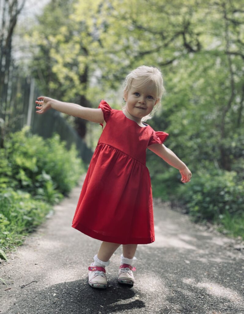 Blonde girl wearing a red summer dress with ruffled sleeves