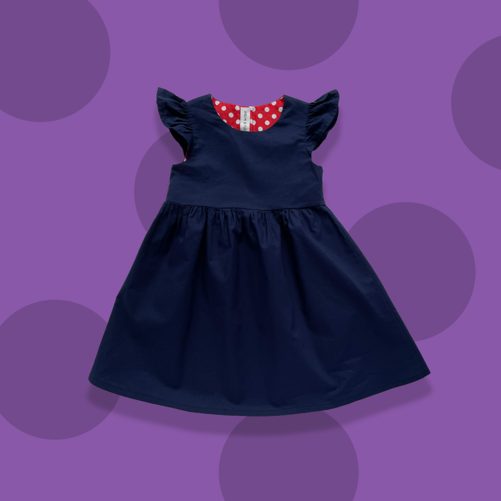 Navy blue girls dress with ruffled sleeves and red and white polka dot lining